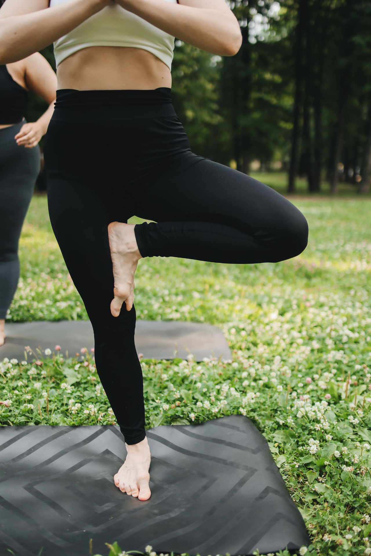 Participants practicing mat Pilates outdoors in a park